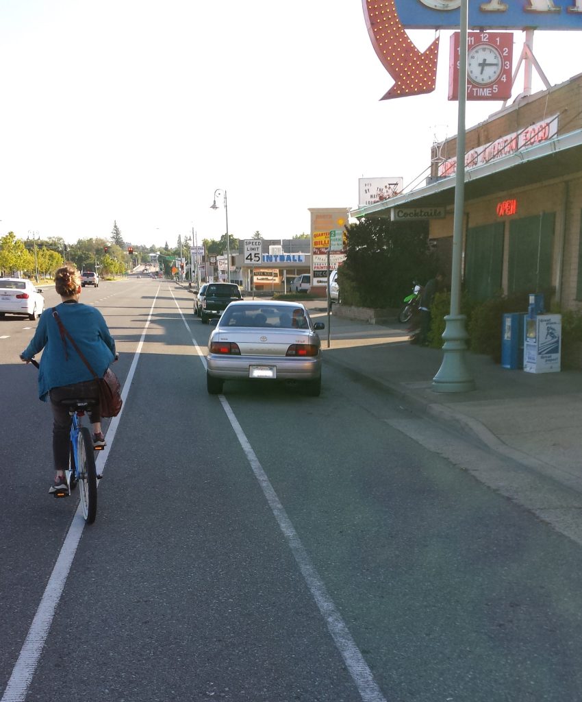 A person bicycling along a multimodal street in the Shasta region